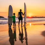 father and son surfers sunset