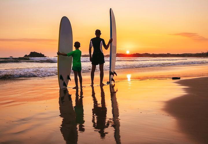 father and son surfers sunset